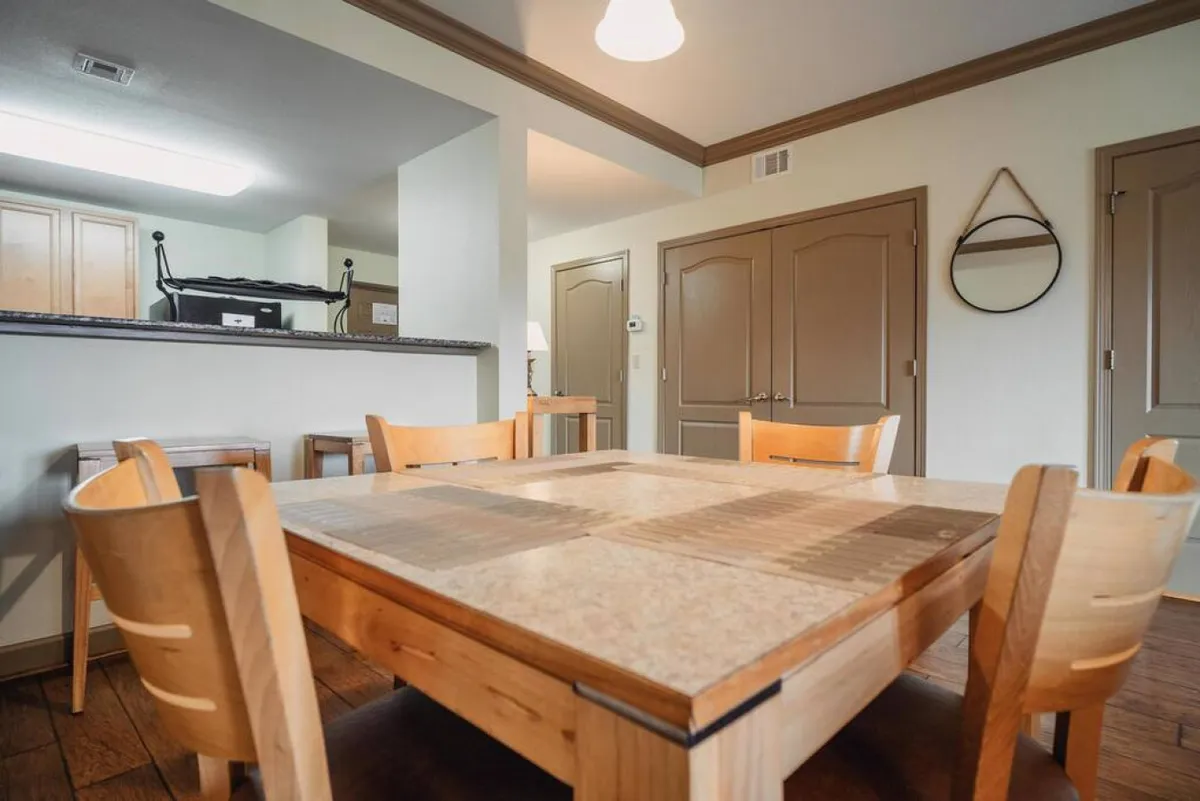Shown here is a spacious dining area with a wooden table and several chairs, seamlessly connected to a kitchen area. The setup is perfect for group meals, celebrations, or casual family gatherings after enjoying the resort's amenities.
