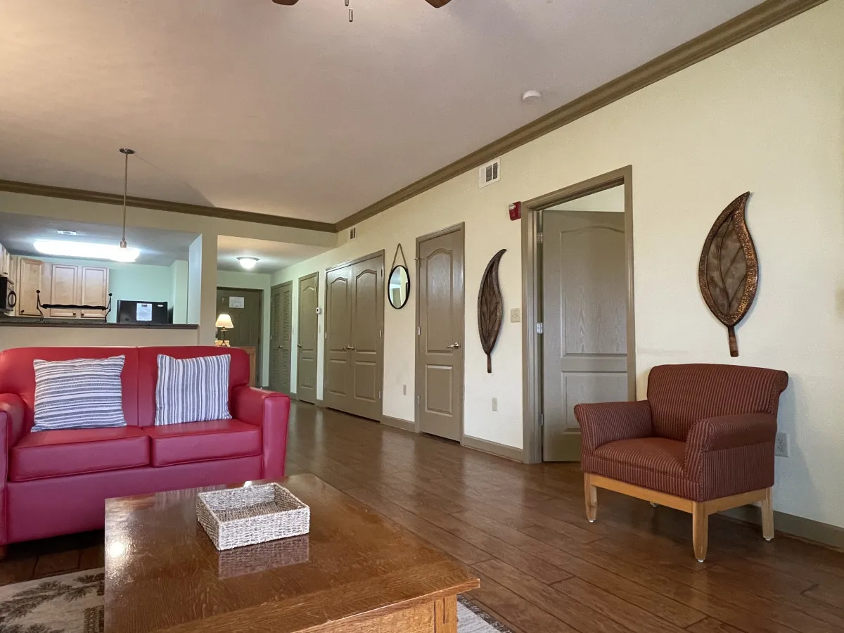 A red sofa and wooden coffee table anchor a warmly decorated living space, complemented by decorative wall art. The setting invites relaxation, socializing, and cozy evenings—ideal for movie nights or chatting after a day of adventure.
