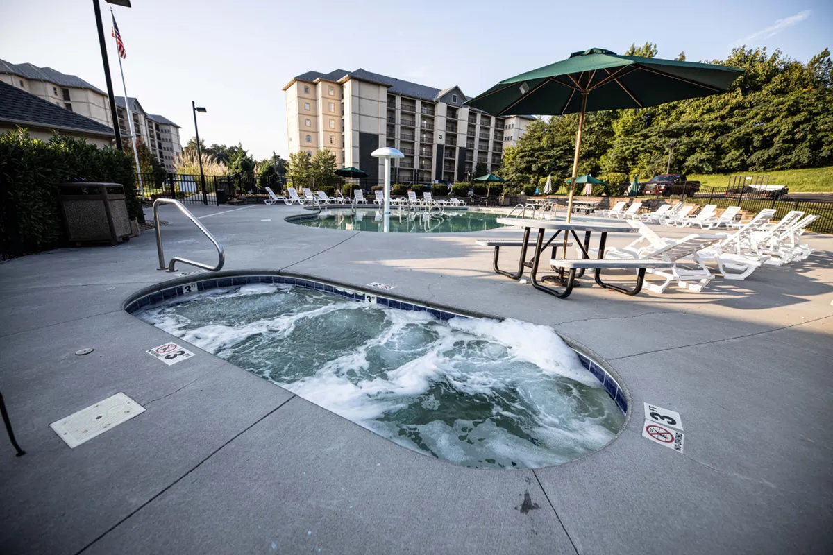 This lively exterior shot features a sparkling swimming pool, inviting hot tub, lounge chairs, and an umbrella-topped table. The atmosphere is laid-back and social, perfect for unwinding after days of adventure or enjoying time with family and friends.