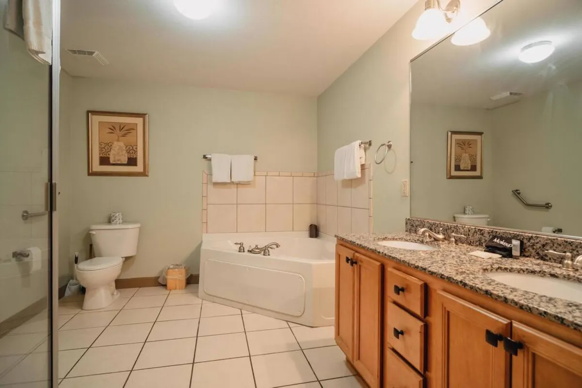 A serene en suite bathroom with a bathtub, double vanity, and framed artwork. The space is designed for relaxation and self-care, with calming colors and an organized layout.