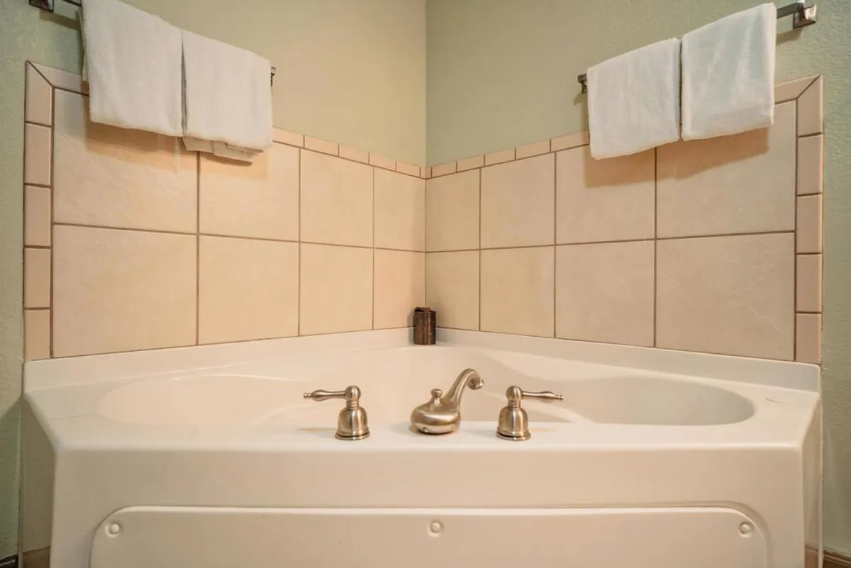 A tranquil bathroom scene featuring a jacuzzi tub, neatly folded towels, and tiled surroundings. The mood is one of relaxation and comfort, perfect for unwinding after an active day.